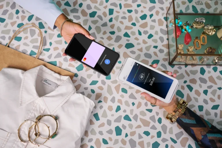 Phone tapping a Smartpay terminal over terrazzo counter with clothing and accessories around