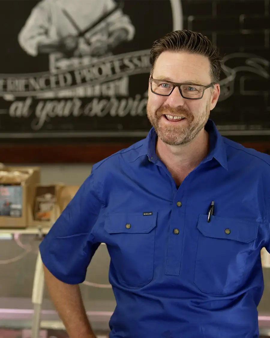 Man in blue shirt standing infront of butchery
